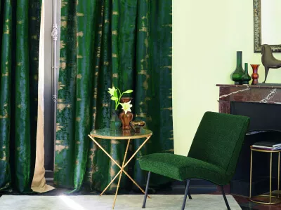 Ein Wohnzimmer mit schweren gefütterten Vorhängen aus grün-, blau- und beige changierendem Jacquardstoff.
