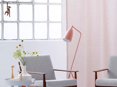Ein rosafarbener und blickdichter Vorhang aus Wolle in einem Altbauraum mit eleganten Retro-Sesseln.