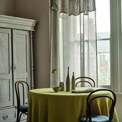 Transparente Leinengardinen und Querbehang in grün-grauer Farbe in einem Esszimmer mit Tisch und Stühlen