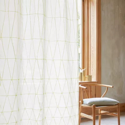 Weißer Vorhang mit grünem Rautenmuster in einem Raum mit natürlichem Holz