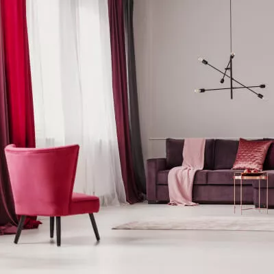 Roter Samtvorhang und weißer Store in Wohnzimmer mit Sofa und Stuhl und Kissen