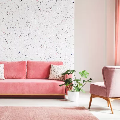 Wohnzimmer mit Couch und Samtbezug sowie Stuhl und transparenter Gardine in rosa