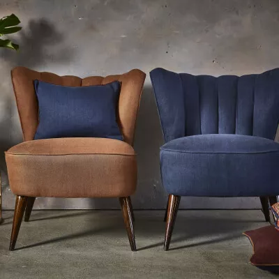 Zwei stilvolle Sessel in Braun und Blau vor grauem Hintergrund