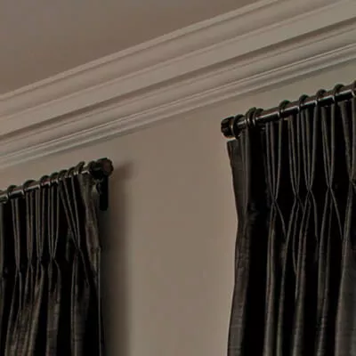 Schwarze Vorhänge im klassischen Stil mit Faltenband hängen mit Metallringen an einer Gardinenstange.
