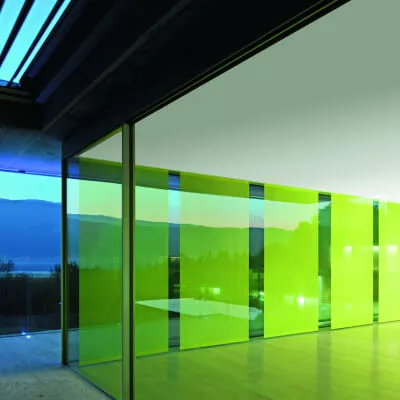 Ein moderner Raum mit grünen Schiebegardinen vor einer sehr großen Fensterfront.