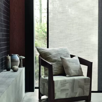 Stuhl und Kissen vor Fenster mit Schiebegardine und Waldsicht