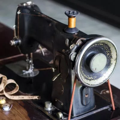 Eine Nahaufnahme von einer alten Nähmaschine mit einem Maßband im klassischen Stil.