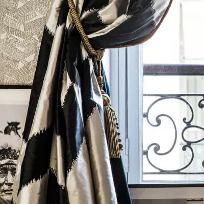 Ein klassischer schwarz-weiss gemusterter Vorhang mit einem goldenen Raffhalter.