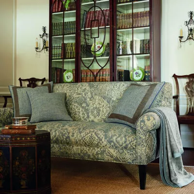 Ambiente im Landhausstil mit einem Sofa in Ornamentoptik mit mehreren Kissen aus Leinen.