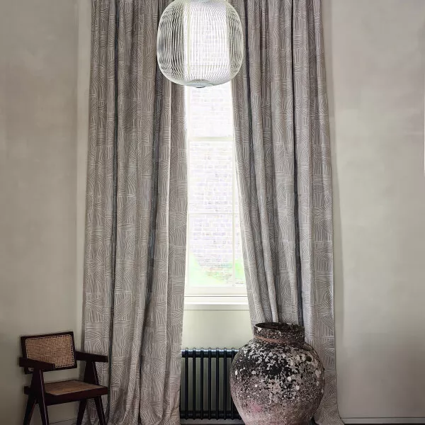 Graubraune Baumwollgardinen vor einem Fenster und eine große Vase auf Parkett