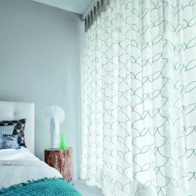 Einen weiße Gardine mit einem modernen Stickmuster mit Linien in Grün und Grau in einem Schlafzimmer