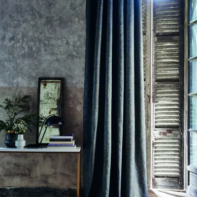 Vintage Szenario mit schwerem, grau-blauem Vorhang am Sprossenfenster und Beistelltisch