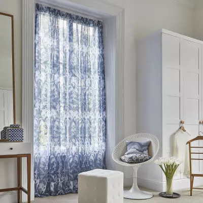 Ruhiges Schlafzimmer: blau-weißer Vorhang, weiße Möbel, Holzdetails.