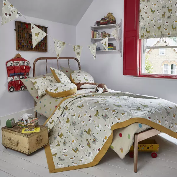 Helles, in violett gehaltenes Kinderzimmer mit einem gemütlichen Bett und abgestimmten Stoffen, dekoriert mit Tiermotiven auf Decken, Kissen, Raffrollo und Vorhängen