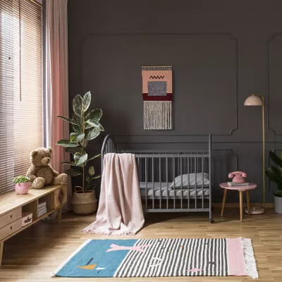 Ein modernes Kinderzimmer in Rosa und Grau mit rosa Vorhang und Jalousien aus Holz.