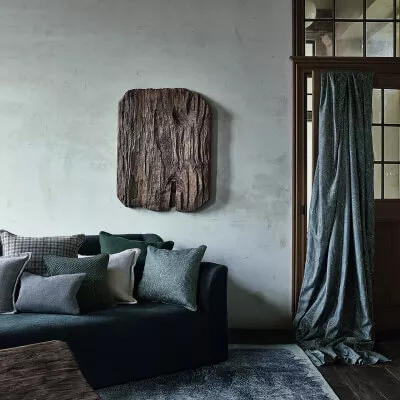 Ruhiger Raum mit blau-grauen Farbakzenten, Holztür mit Glaseinsatz, dunkles Sofa mit grauen Kissen vor blaugrauer Wand.