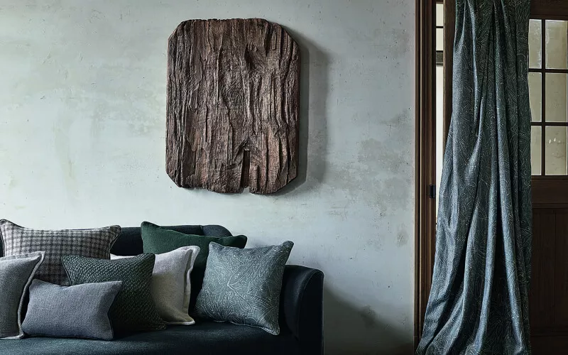Elegant eingerichteter Raum mit dunklem Sofa und Holzobjekt an der Wand
