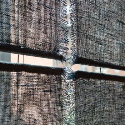 Eine Detailaufnahme von transparenten Schiebegardinen in ausgefranster Leinenoptik.