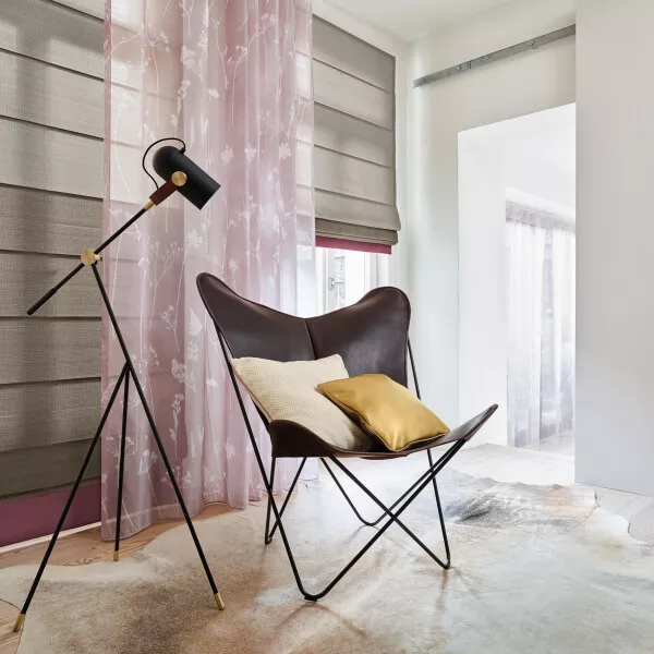 Rosafarbener und transparenter Vorhang mit Raffrollo und Sessel.