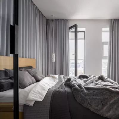Ein luxuriöses Schlafzimmer mit grauen modernen Vorhängen und Bettwäsche in verschiedenen Grautönen.