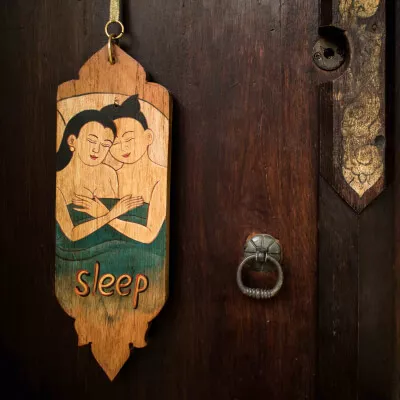 Ein Türschild aus Holz mit sleep-Zeichen hängt an einem Türknauf.